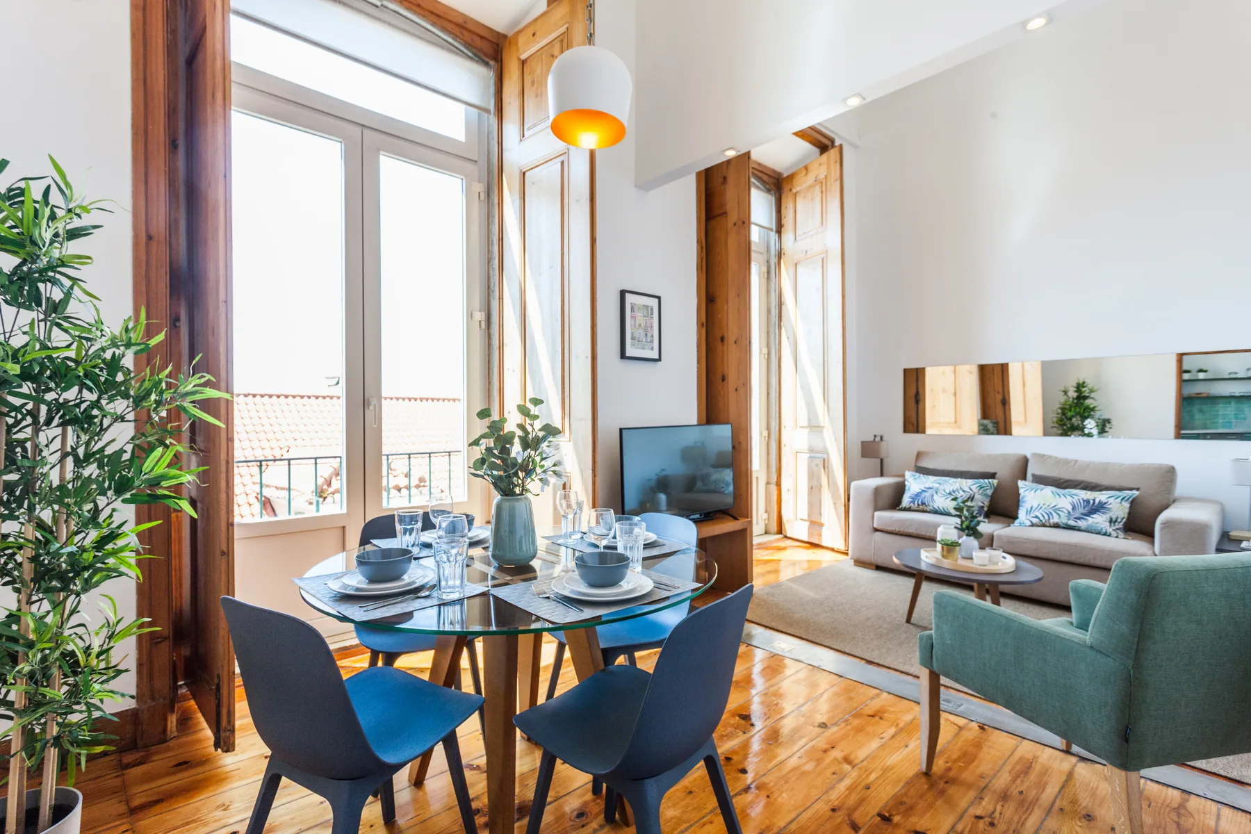 A bright living and dining area with tall windows, a table, and seating.
