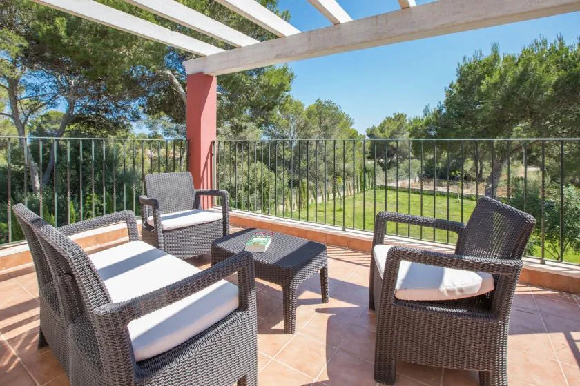 A tiled outdoor terrace with dark wicker seating overlooks green trees.