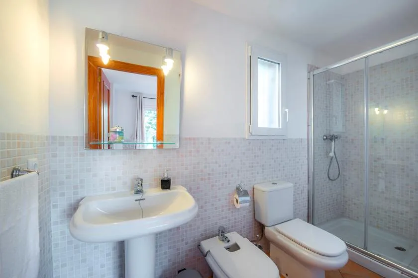 A tiled bathroom with a sink, toilet, and glass shower enclosure.