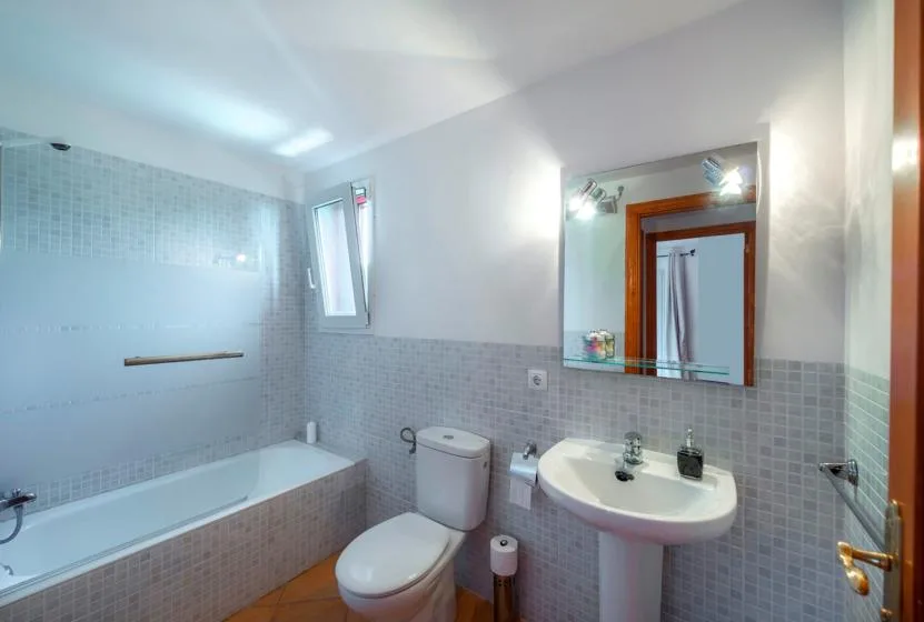 A tiled bathroom with a bathtub, toilet, and sink beneath a mirror.
