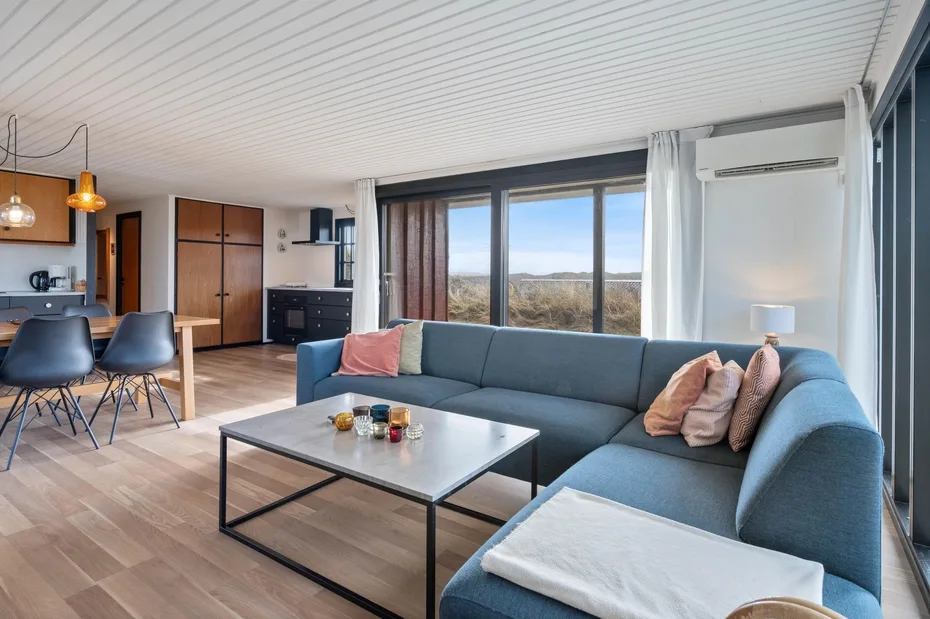 A bright living room with sectional seating beside large windows.