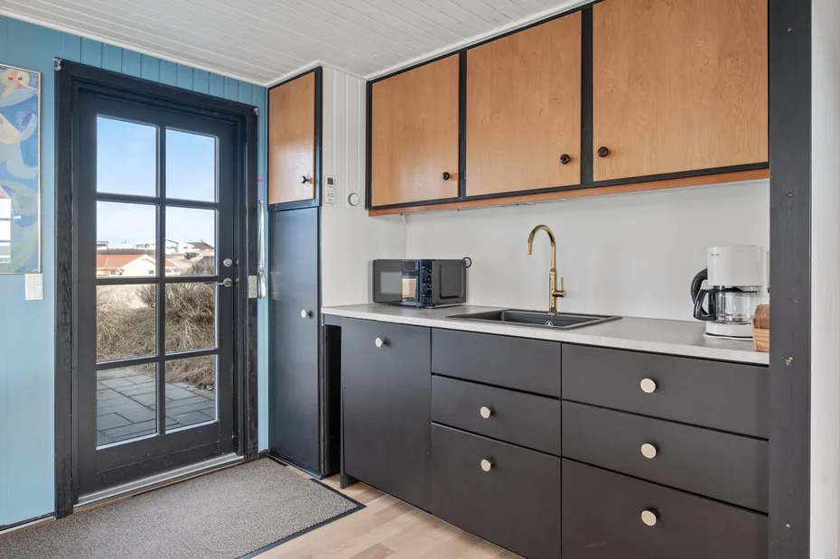 A compact kitchen with dark cabinets and a glass door opening onto a patio.