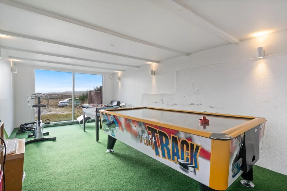 A recreation room features an air hockey table and exercise equipment.