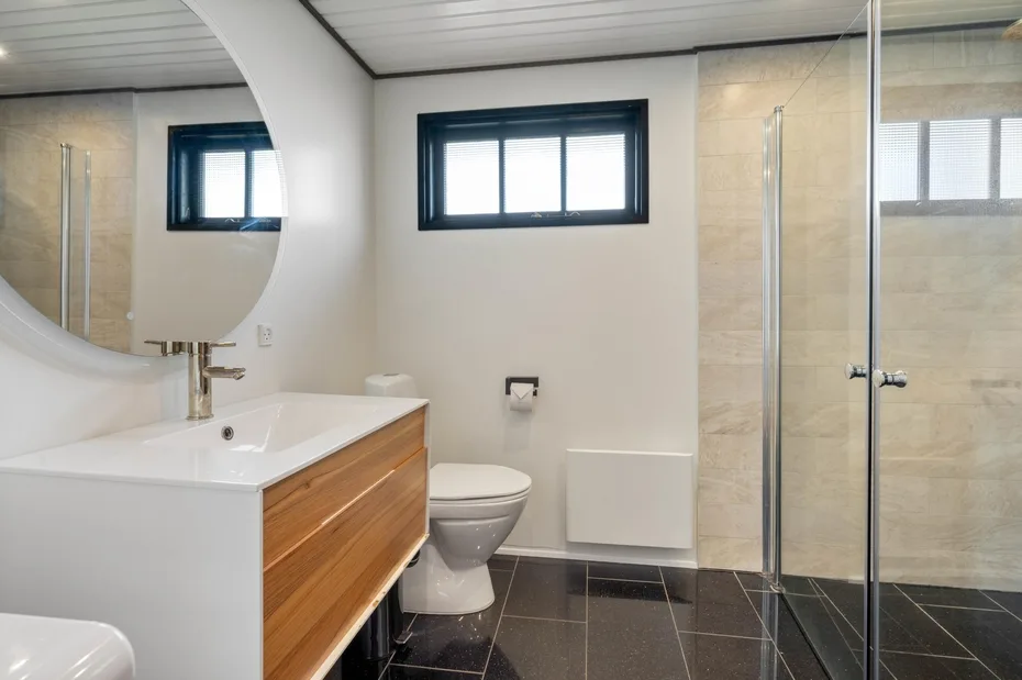 A bathroom with a vanity, toilet, and glass shower enclosure.