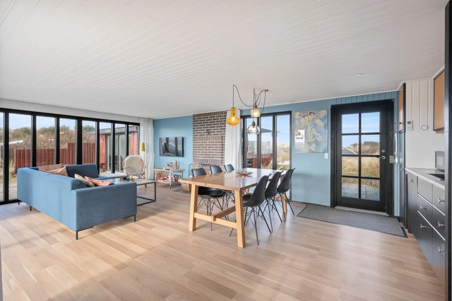 An open-plan living and dining area with blue seating and a wooden dining table.