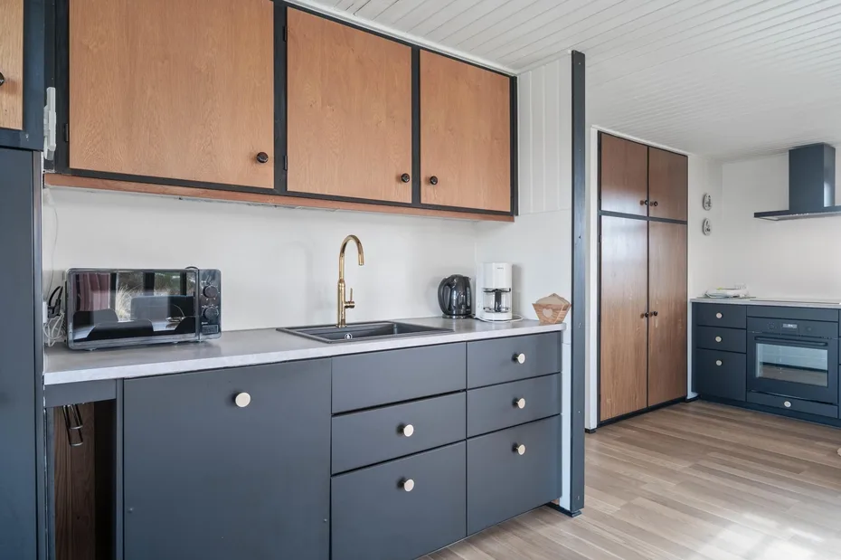 A modern kitchen with dark cabinets, a sink, and countertop appliances.