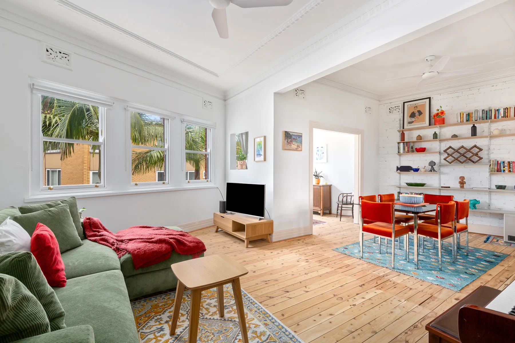 Settle into the light-filled open layout, where leafy views, a TV, colourful furnishings and curated décor create a bright, characterful setting for time at home.