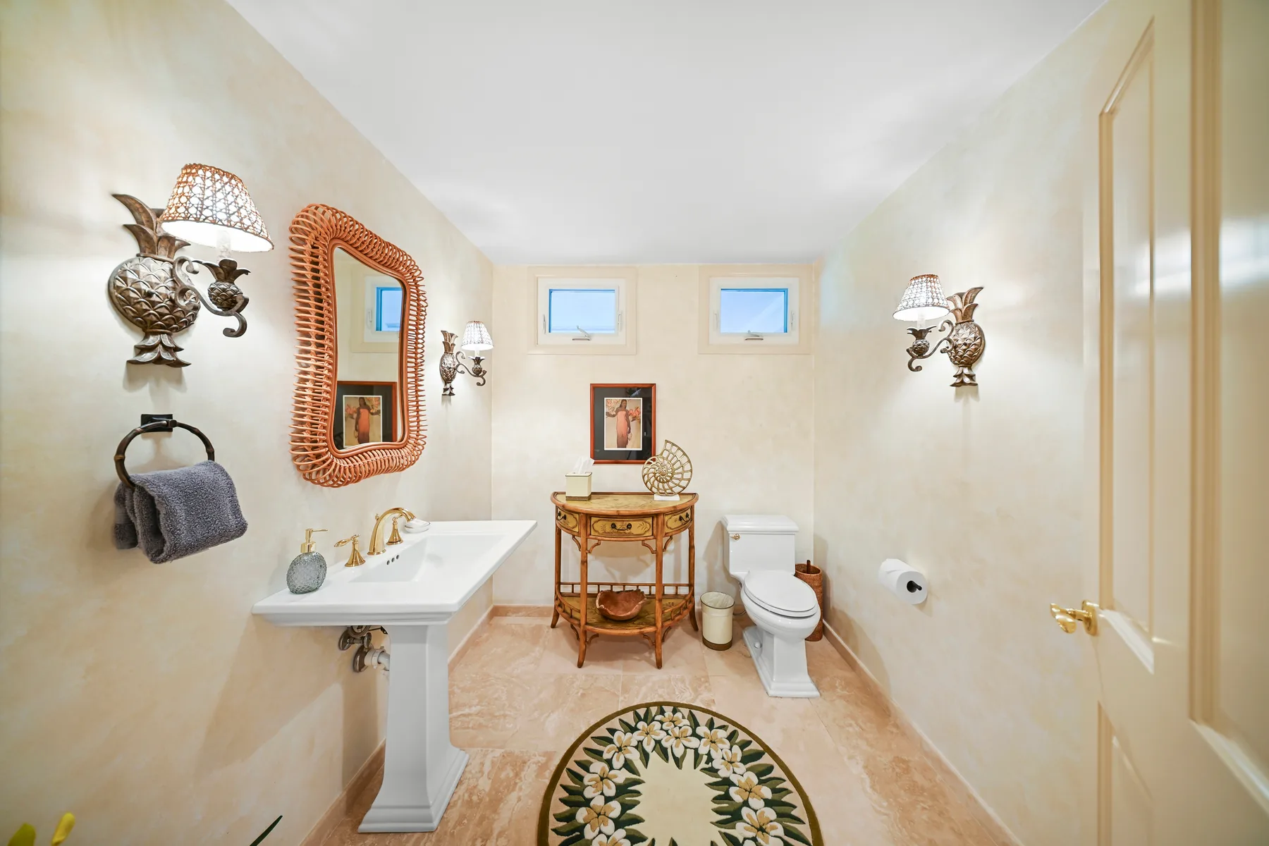 A bathroom with a pedestal sink, toilet, and decorative rug.