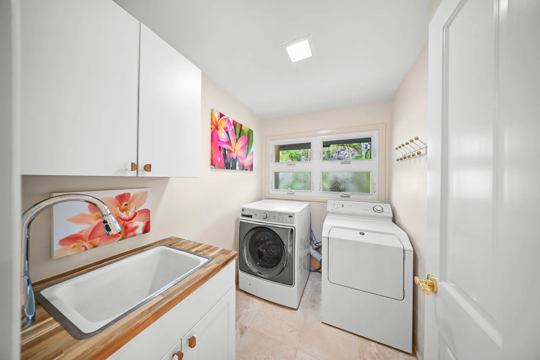 A bright laundry room with a washer and dryer beneath a window.
