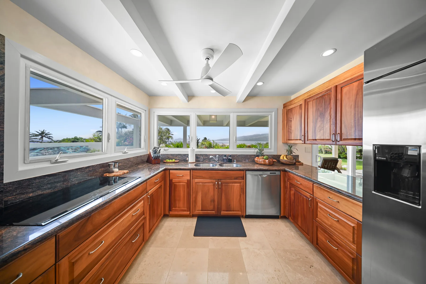 A bright kitchen with wooden cabinetry, stainless steel appliances, and broad windows.