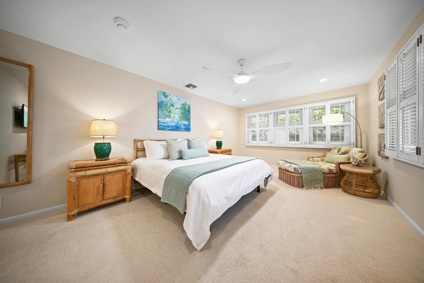 A bright bedroom with a bed, bedside tables, and windows.