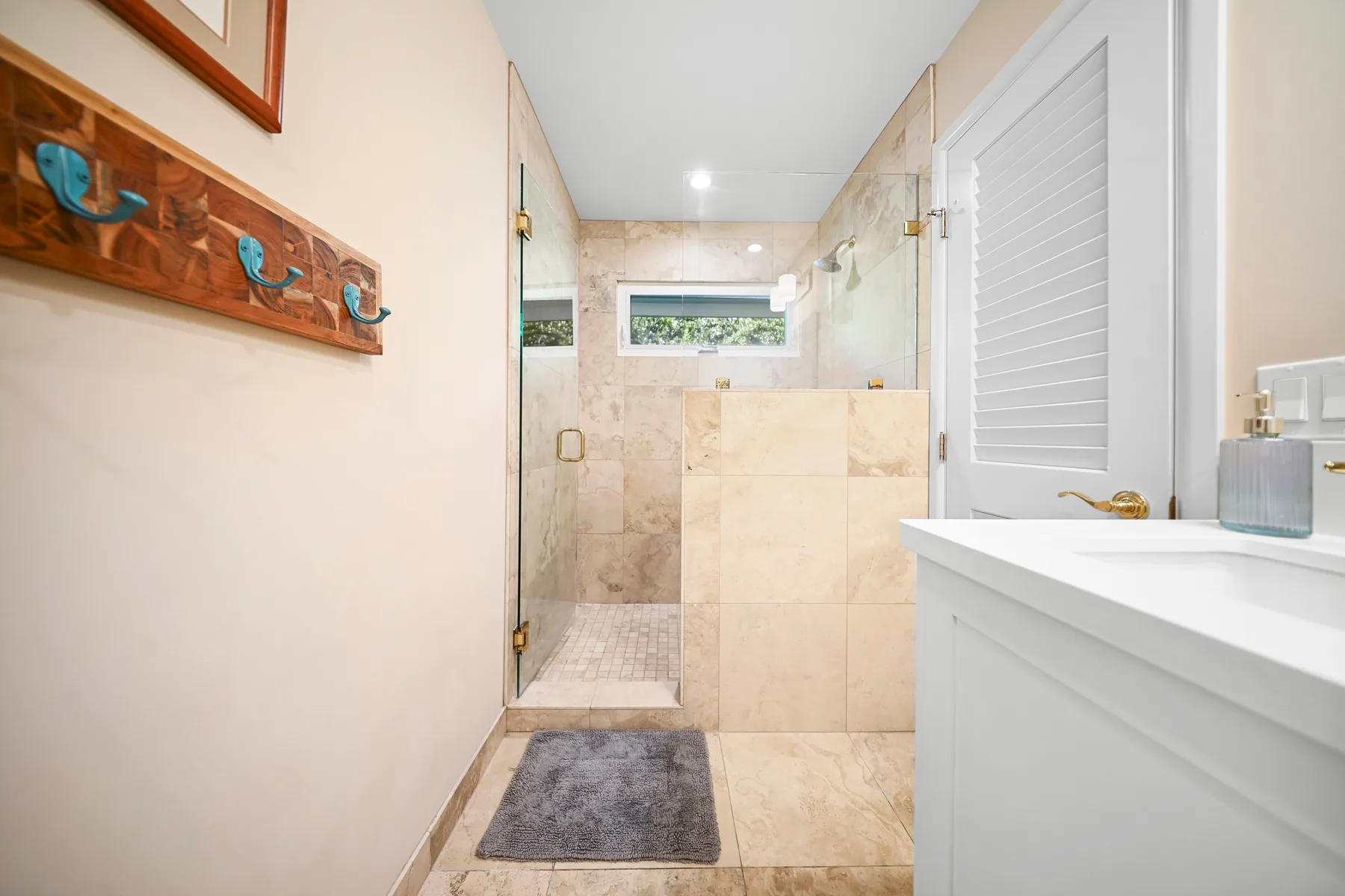 A bright bathroom with a glass shower and white vanity.