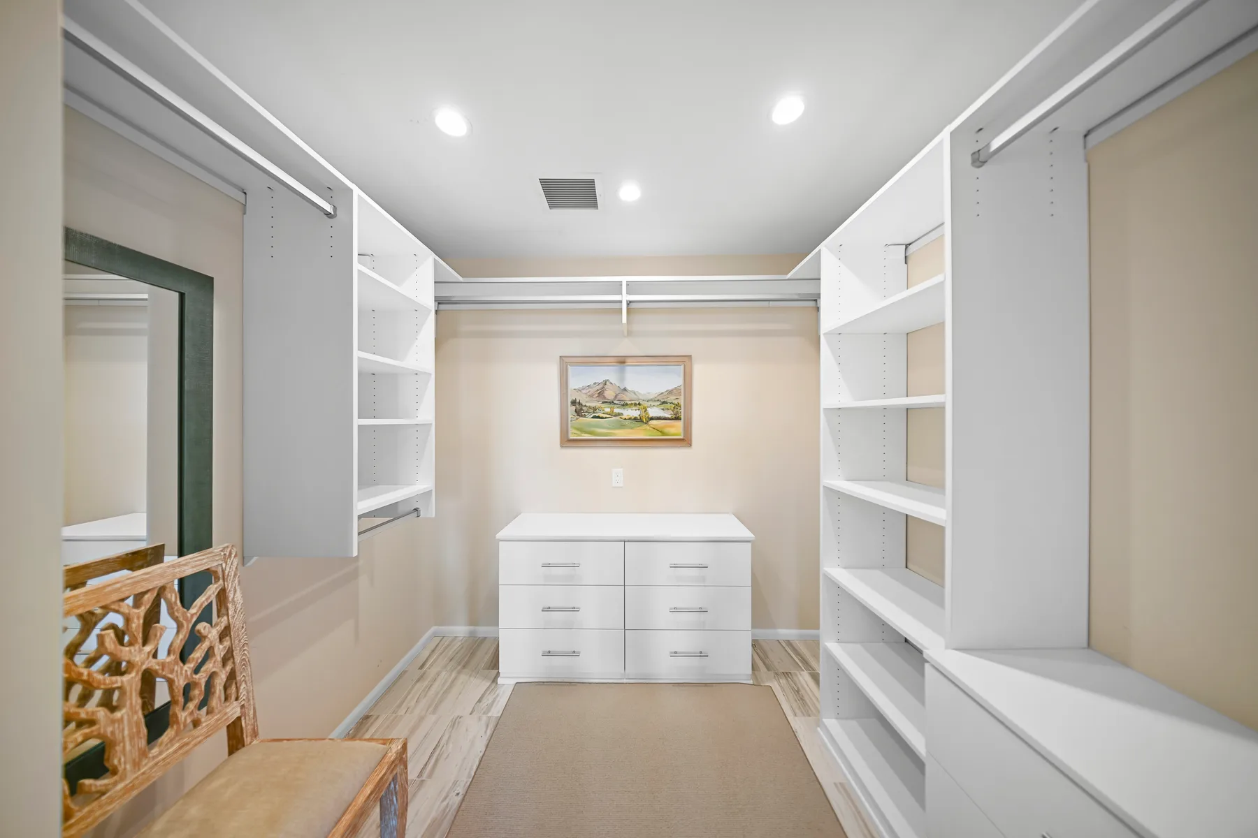A walk-in closet with open shelving, drawers, and a framed picture on the back wall.