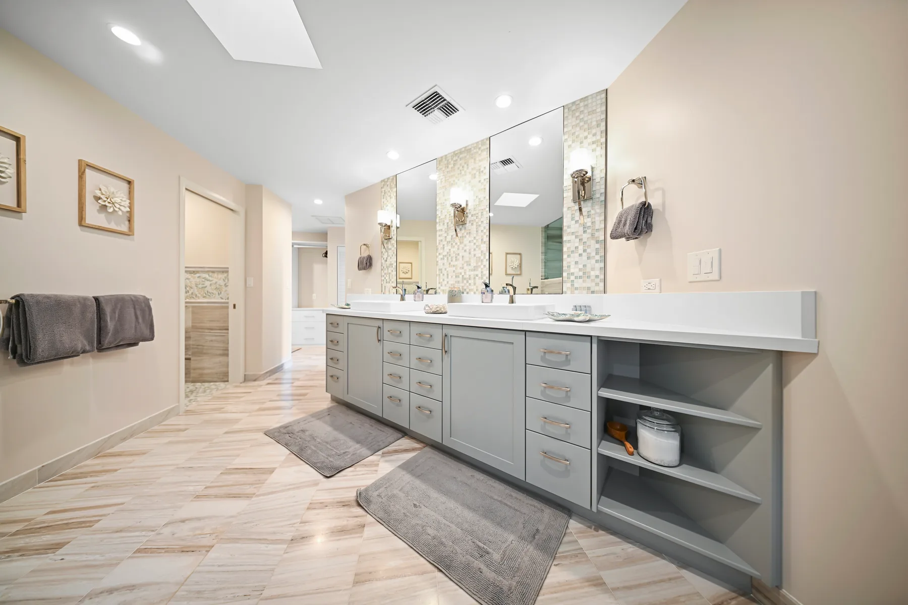 A spacious bathroom with a long vanity, mirrors, and a tiled floor.