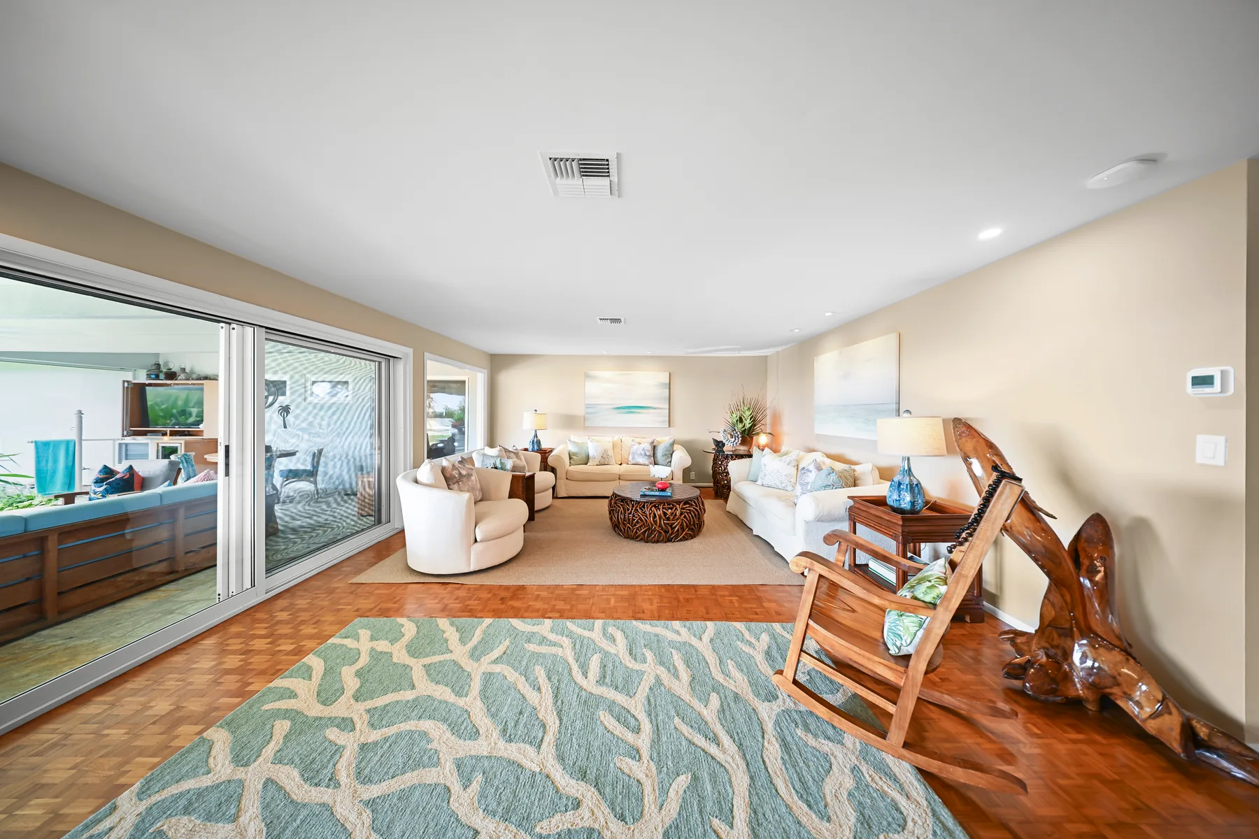 A bright living room with seating, a patterned rug, and sliding glass doors.