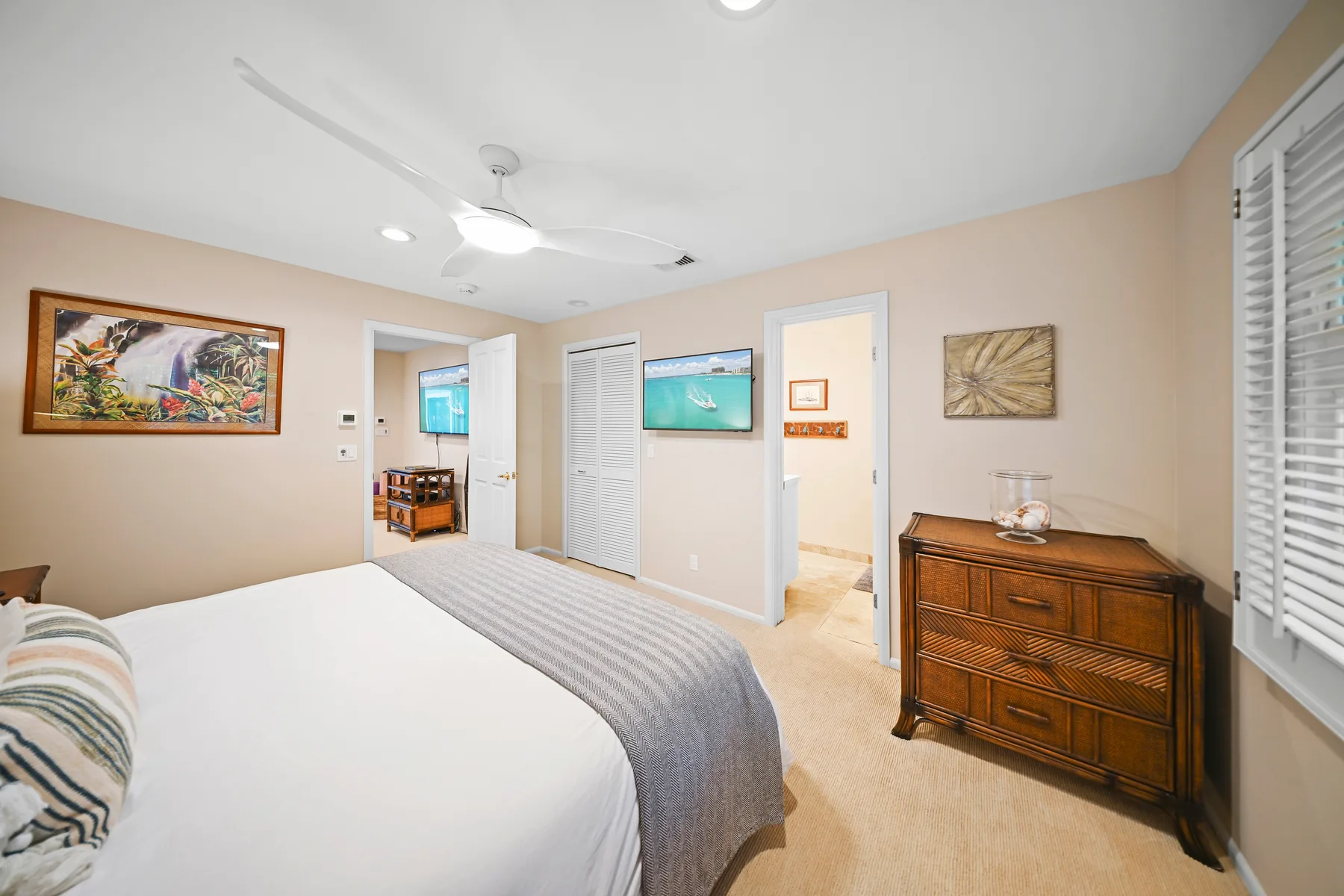 A bedroom with a bed, ceiling fan, and wooden dresser.
