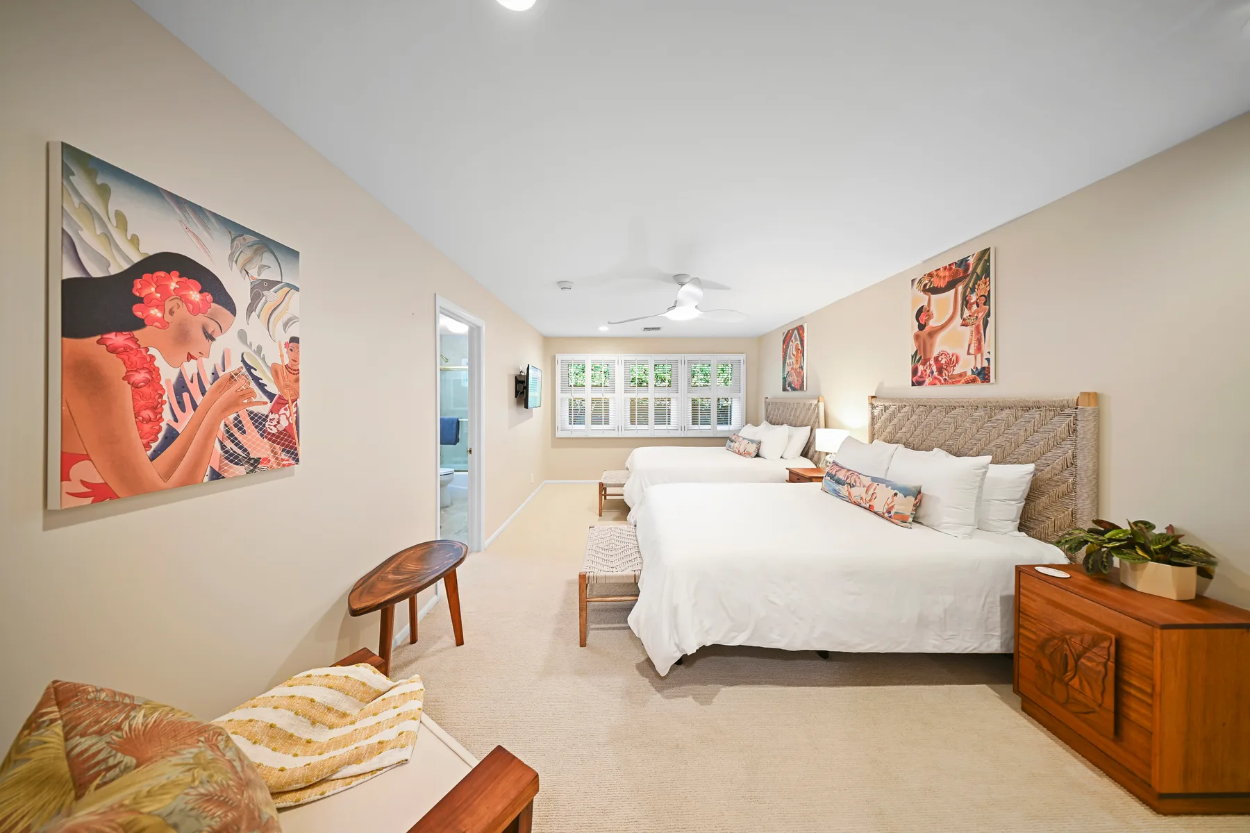 A bright bedroom with a large bed, colorful artwork, and a window.