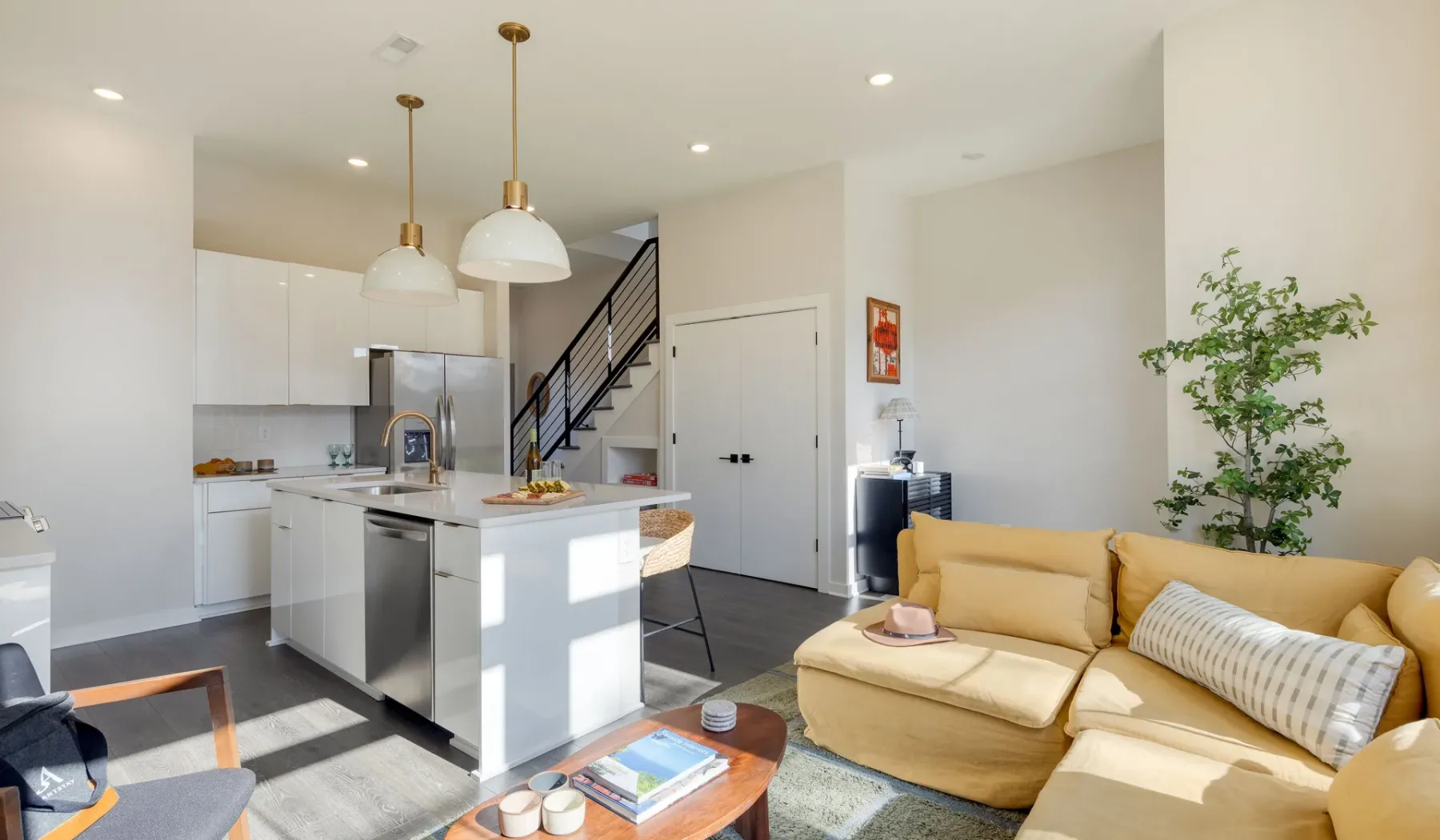 Una sala de estar y cocina de planta abierta con una escalera y una zona de asientos.