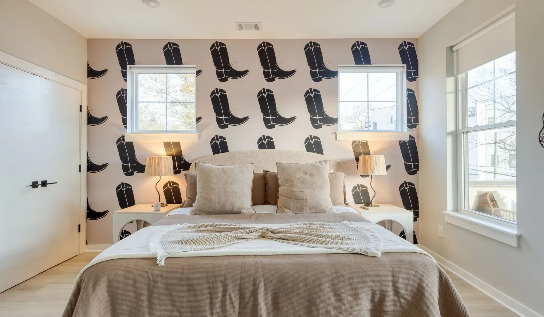 Un dormitorio con una cama, lámparas de noche y papel pintado estampado.