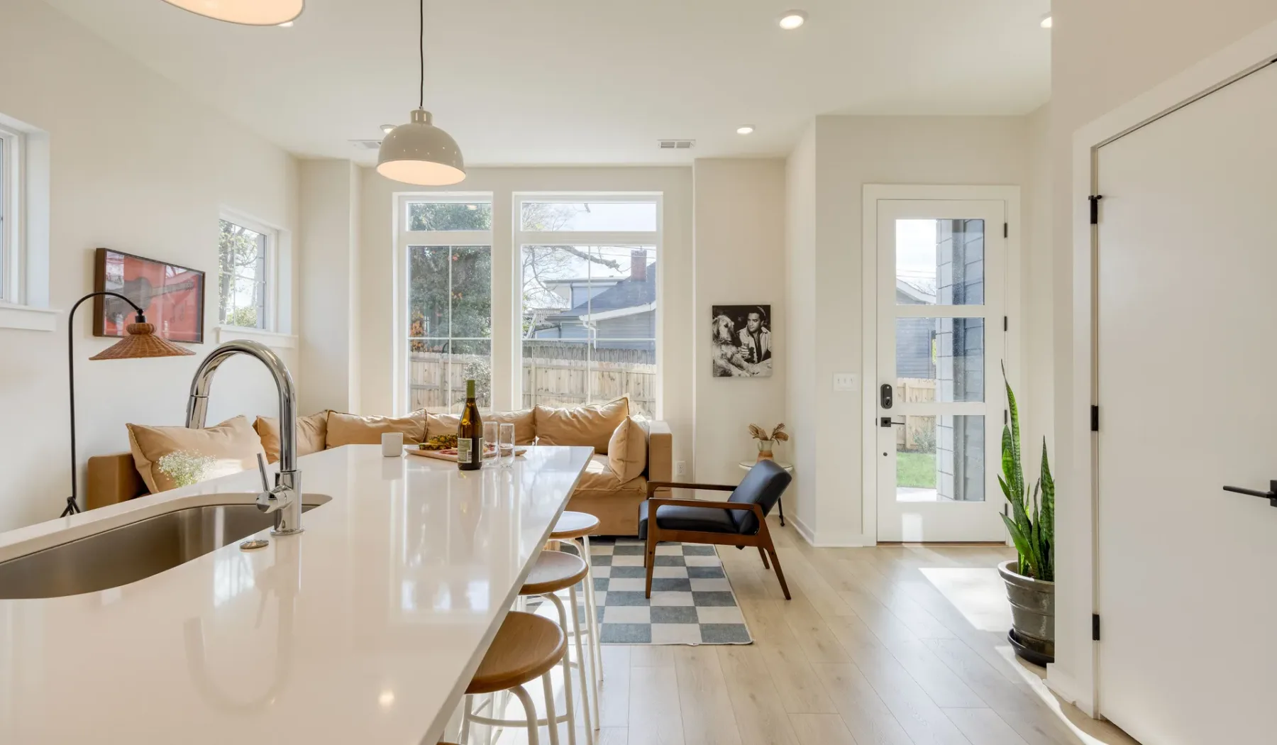 Una luminosa sala de estar diáfana con una isla de cocina y asientos junto a las ventanas.