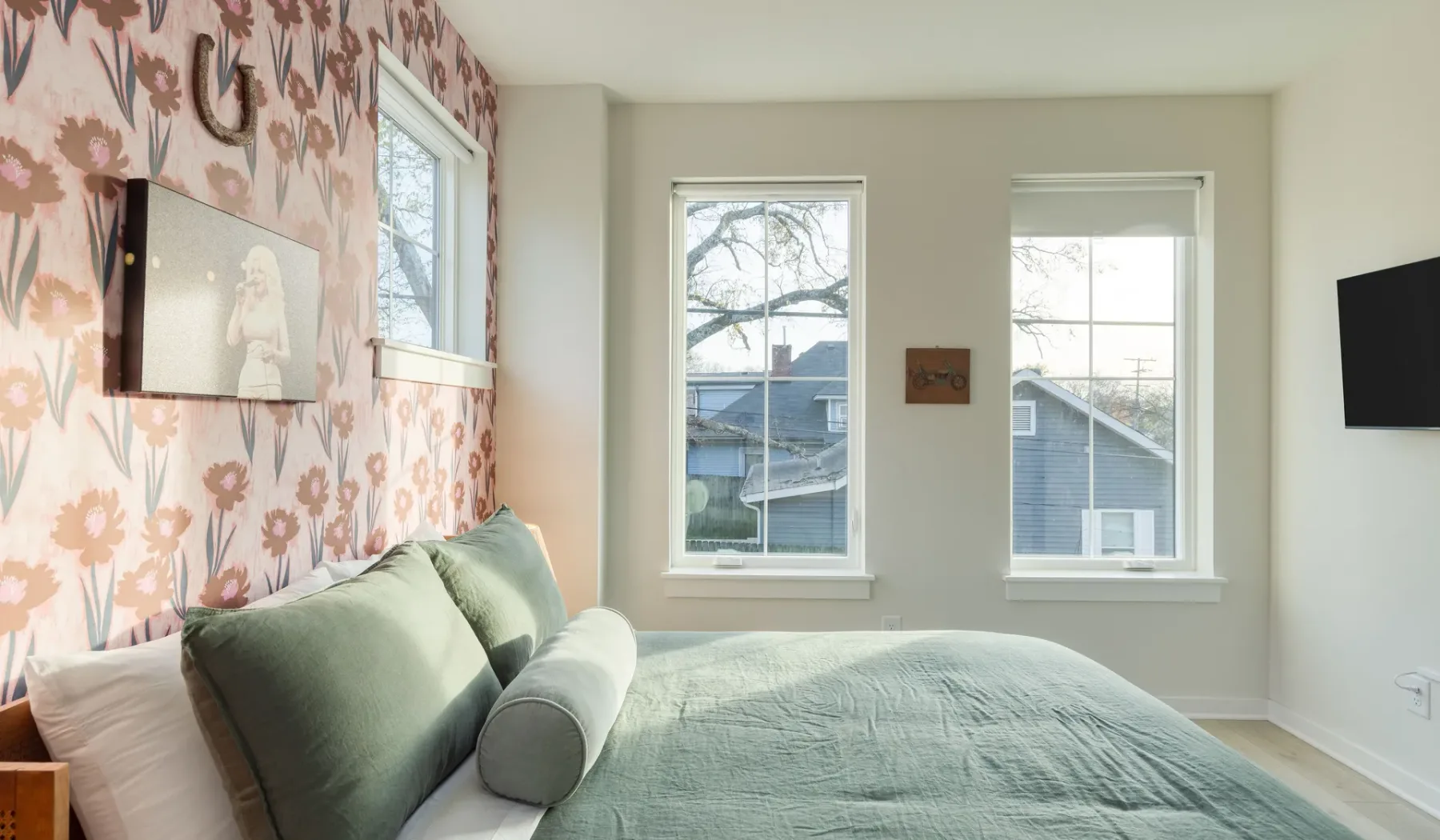 Un dormitorio con una cama, papel tapiz floral y dos ventanas.