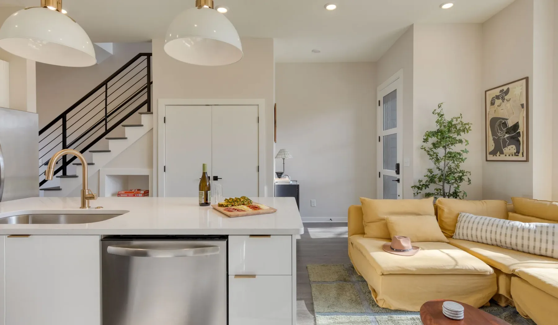 Una luminosa cocina abierta al salón con un sofá seccional amarillo.