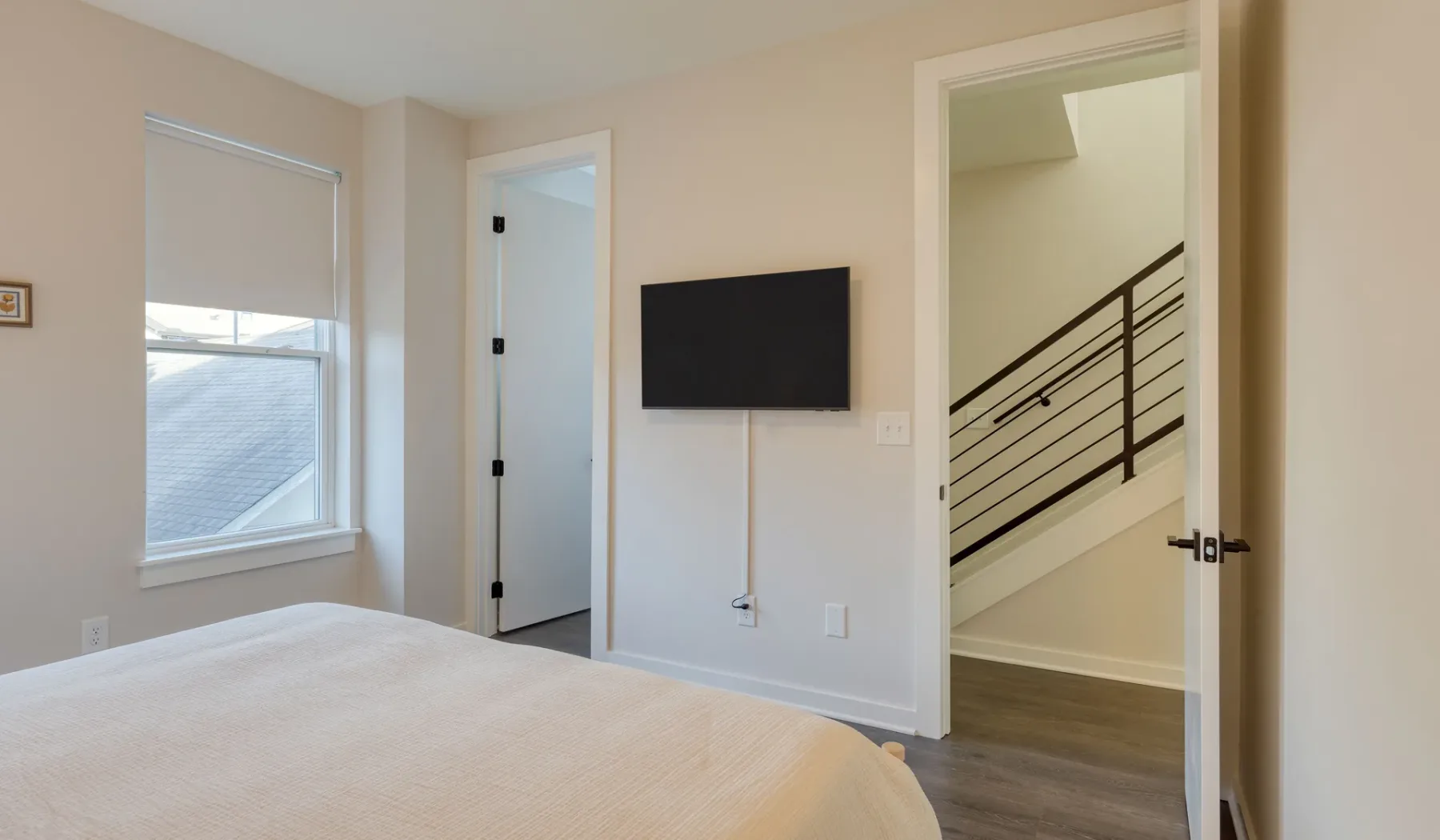 Un dormitorio con un televisor en la pared y vista a la escalera.