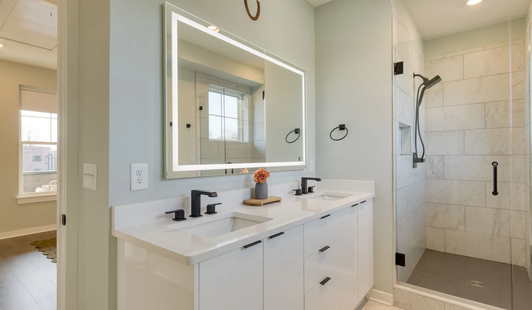 Un baño luminoso con tocador doble y ducha con azulejos.