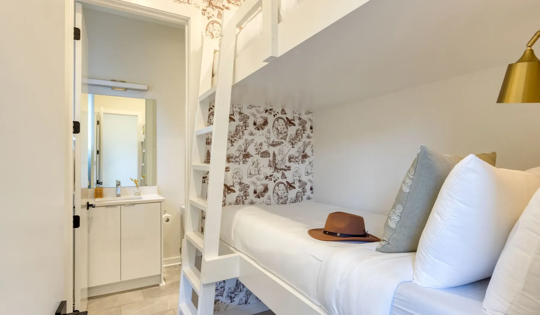 Un dormitorio compacto con cama blanca, pared estampada y tocador contiguo.