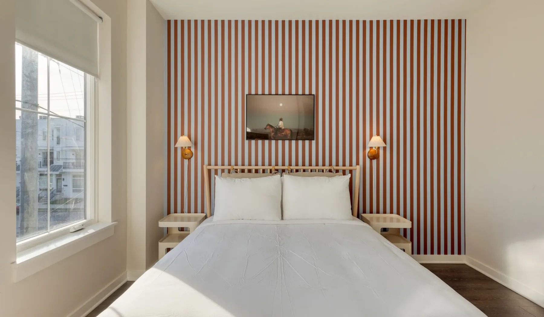 Un dormitorio con una cama tendida junto a una pared decorativa a rayas.