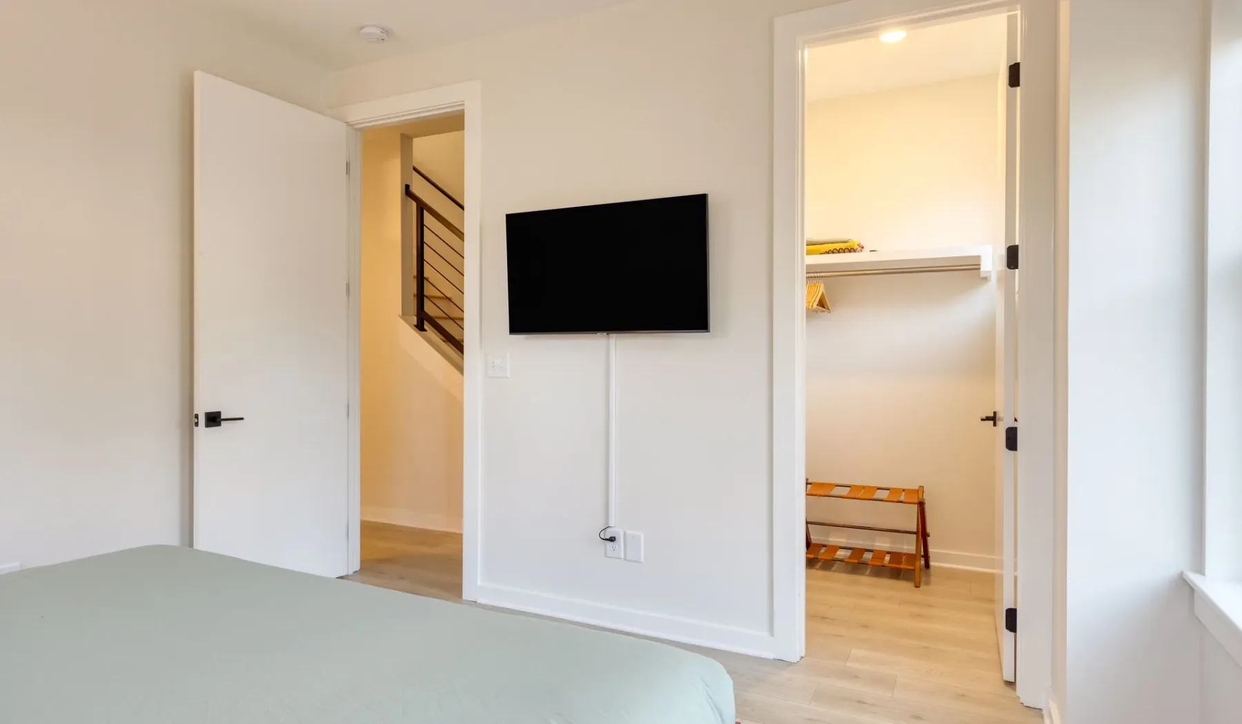 Un dormitorio con un televisor montado en la pared y un armario abierto.