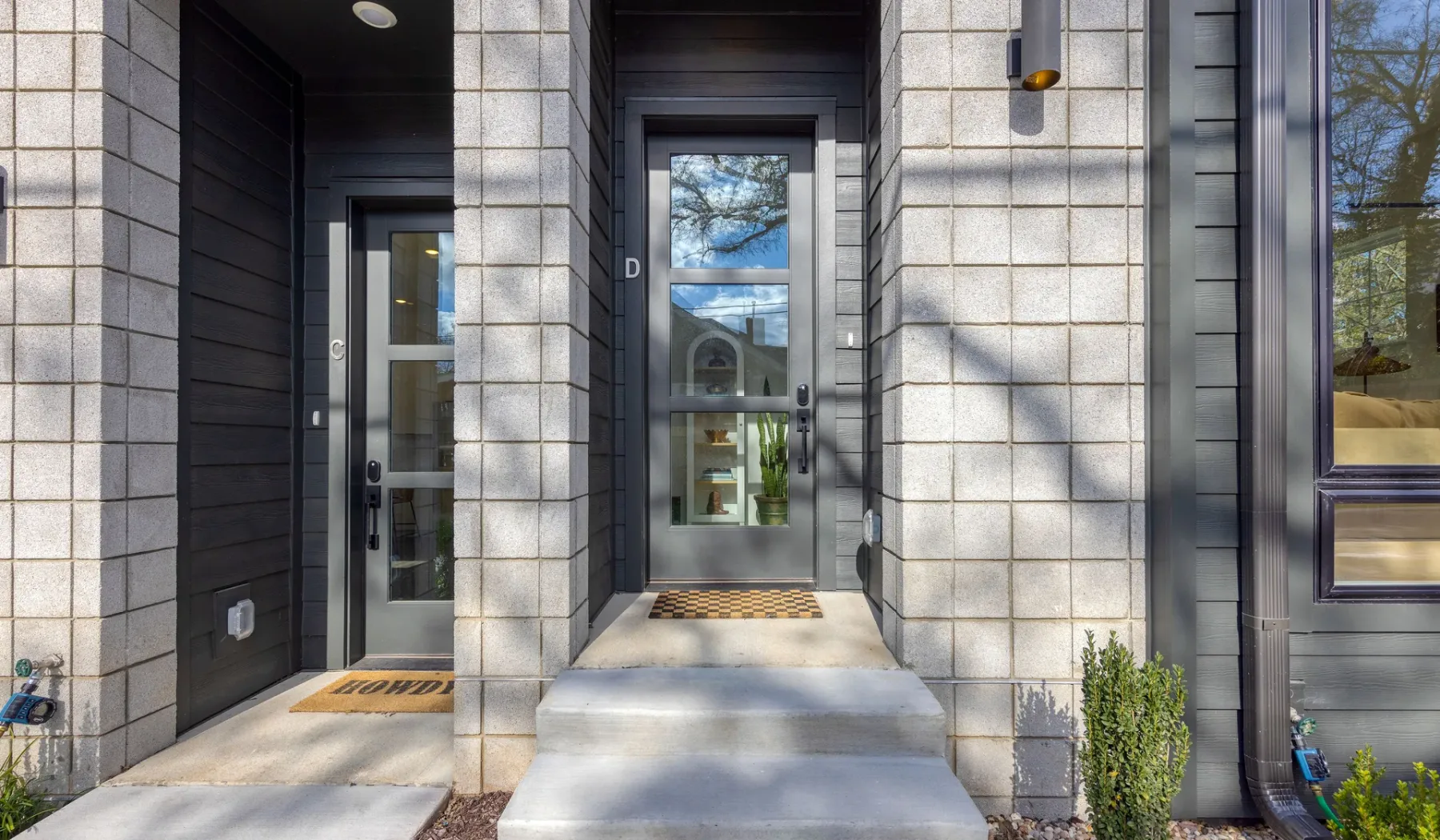 Entrada de un edificio moderno con puerta de vidrio y amplios escalones de concreto.