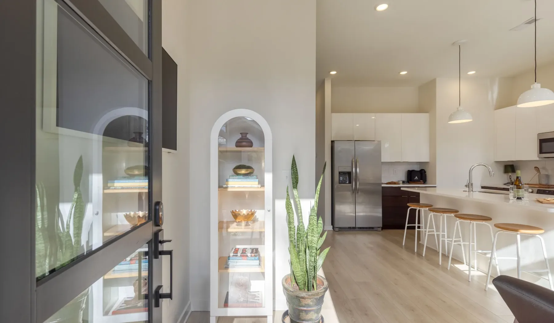 Una cocina luminosa con una isla para comer, lámparas colgantes y un refrigerador.