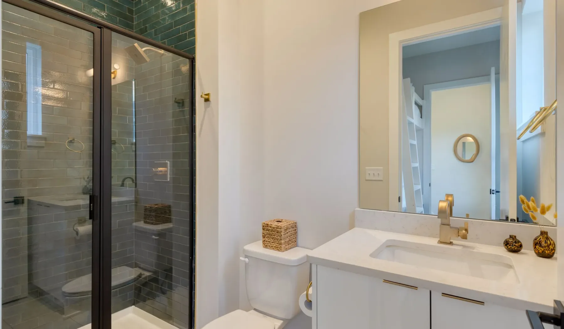 Un baño con una ducha de vidrio y un lavabo blanco bajo un espejo.