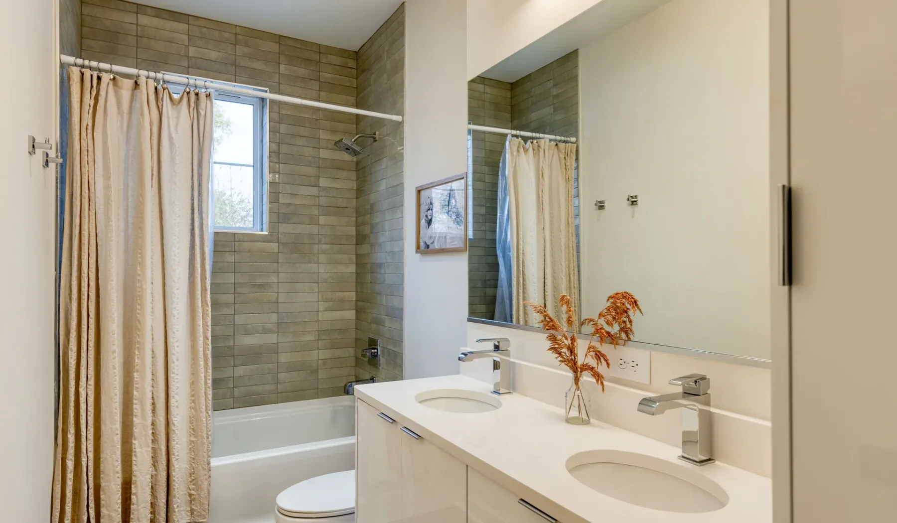 Un baño con bañera, cortina de ducha y tocador con dos lavabos.