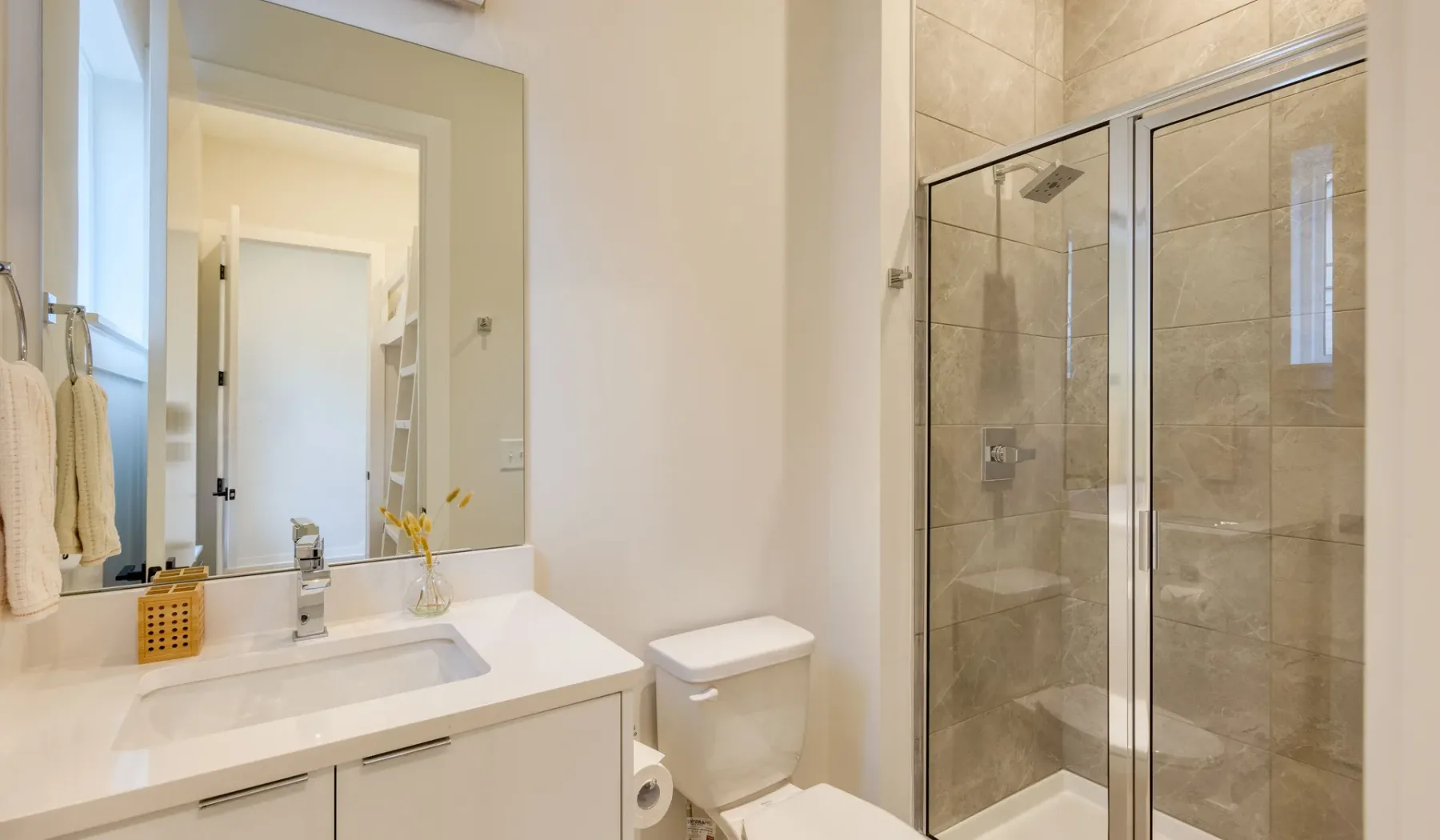 Un baño luminoso con lavabo, inodoro y ducha con mampara de vidrio.