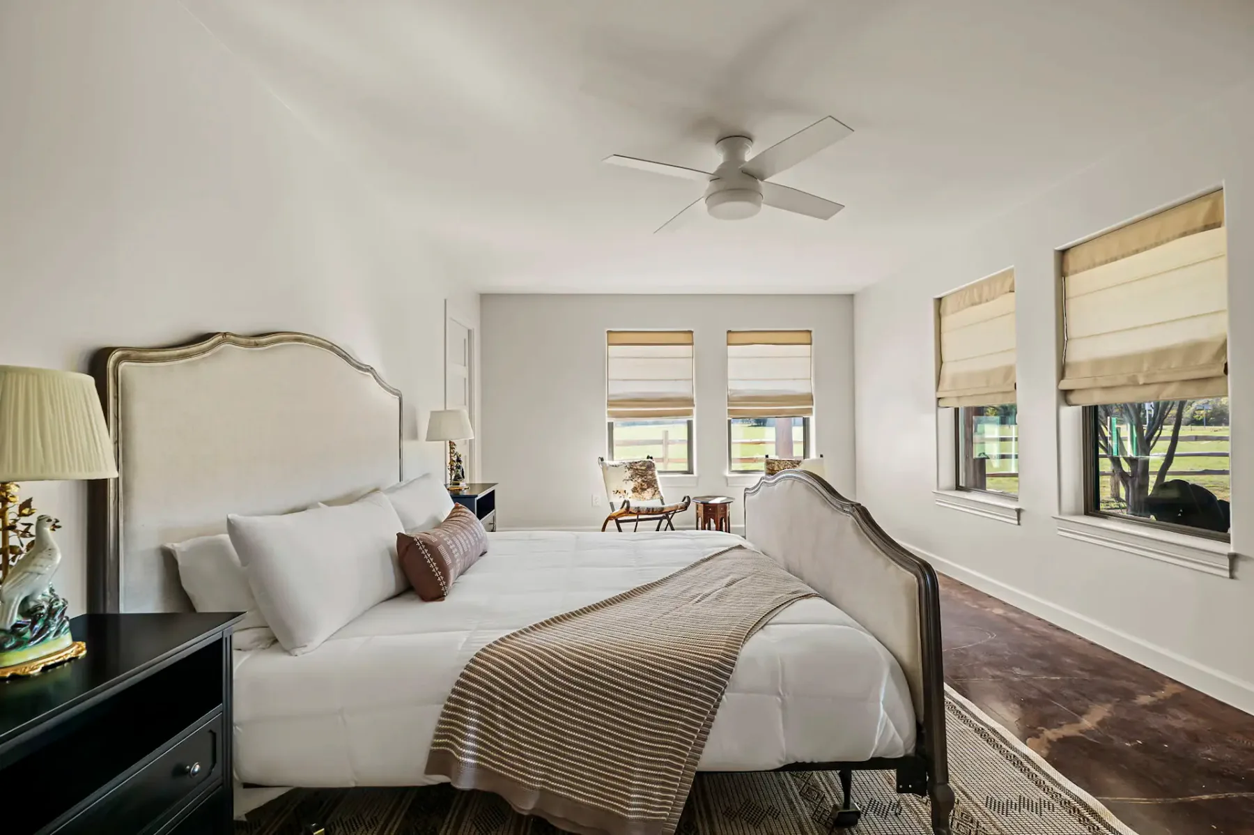Un dormitorio luminoso con una cama grande y ventanas a lo largo de una pared.