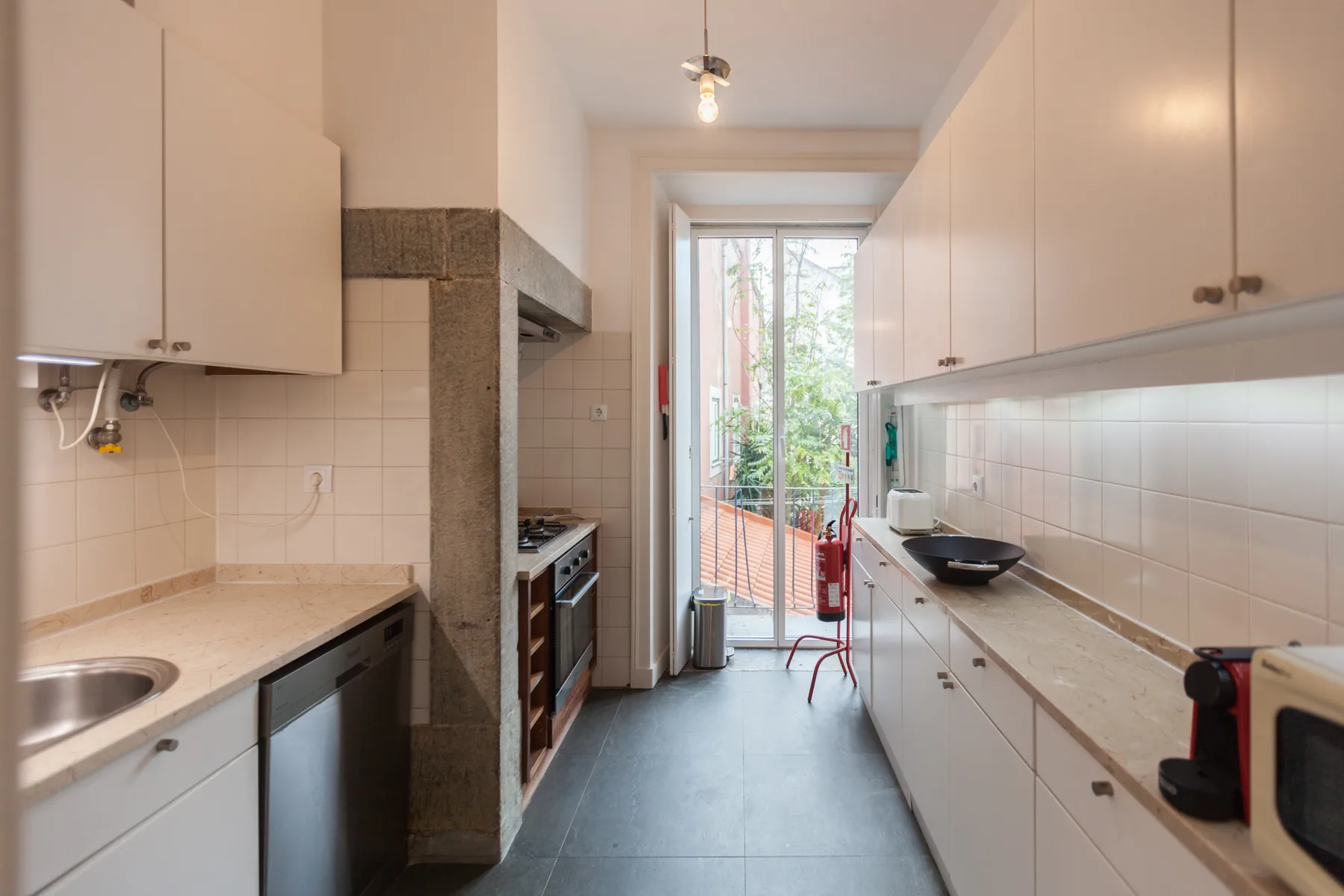 Una cocina estrecha con encimeras largas y una puerta de cristal que da a un balcón.