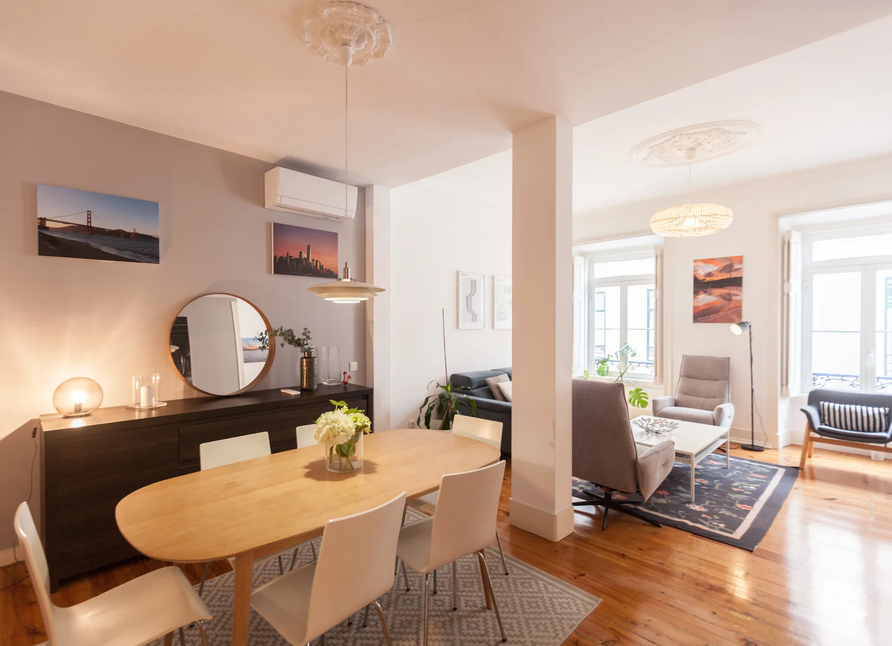 Comedor y sala de estar con una mesa de madera, asientos y ventanas amplias.