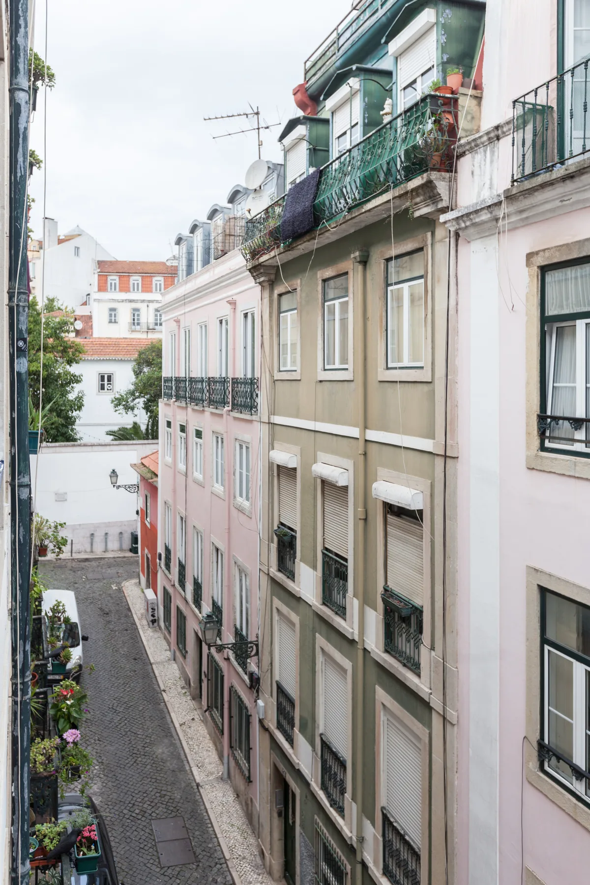 Una calle estrecha empedrada pasa entre edificios de colores pastel con balcones.