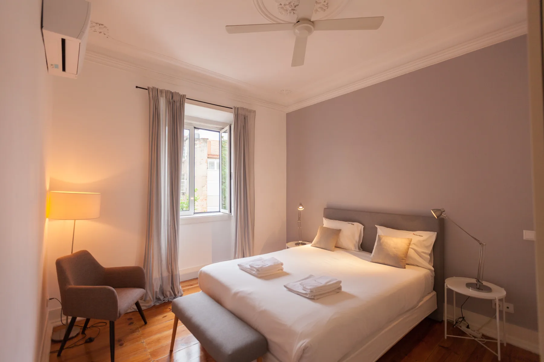 Un dormitorio con una cama bien hecha y una ventana enmarcada por cortinas.