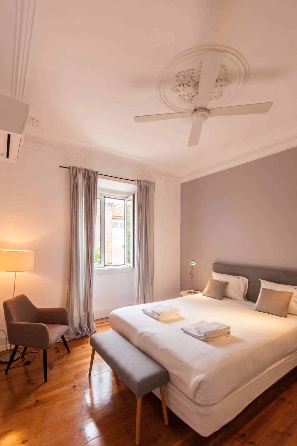 Dormitorio con una cama grande, una ventana y una pequeña zona de estar.