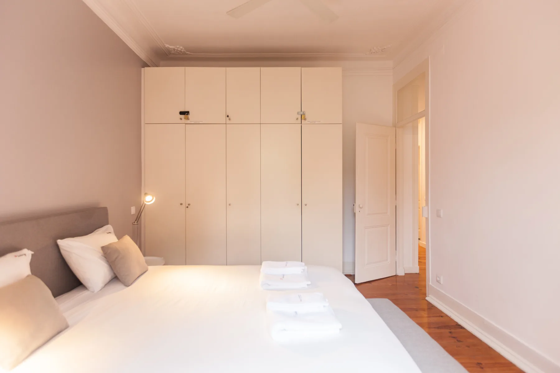 Un dormitorio con una cama, una lámpara de noche y armarios empotrados.