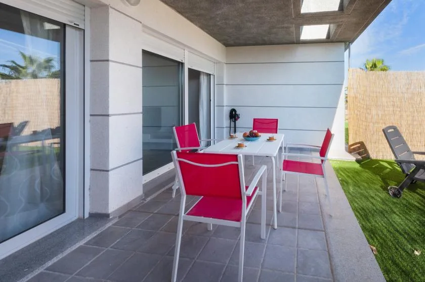 A covered outdoor dining area with a table and bright red seating.