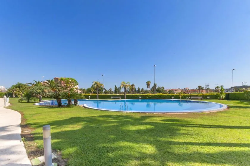 A landscaped outdoor pool sits beside a broad lawn and a curving paved path.