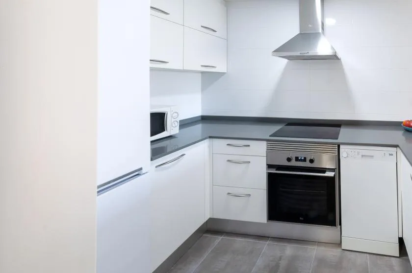 A white kitchen with built-in cabinets, a cooktop, and an oven.