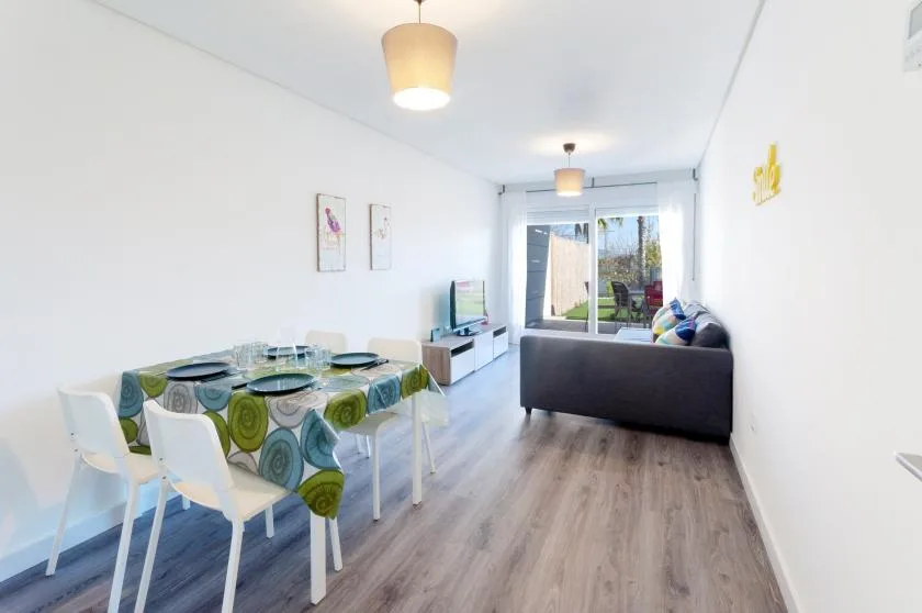 A bright living and dining room with a table and seating beside glass doors.