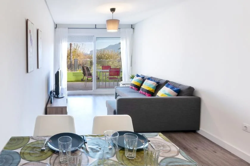 A bright living and dining area with seating beside sliding glass doors.