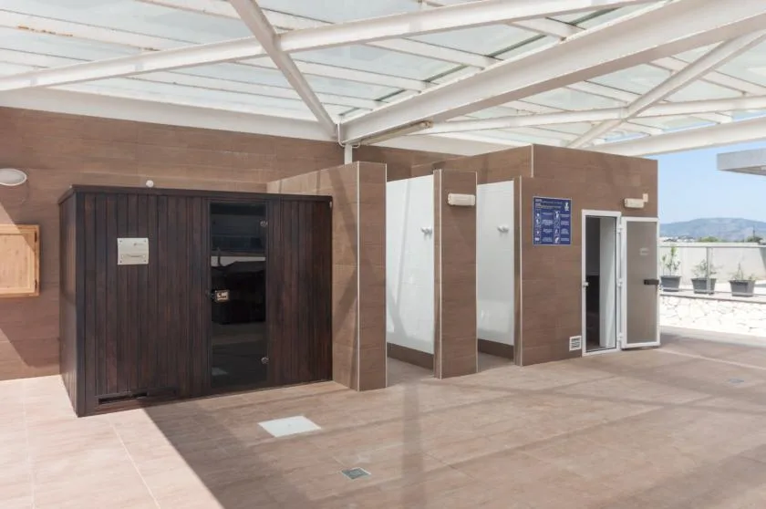 A covered outdoor changing area has several doors along a brown wall.