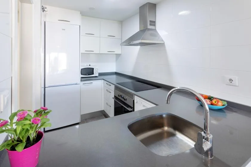 A bright modern kitchen with white cabinets, a countertop, and a sink.